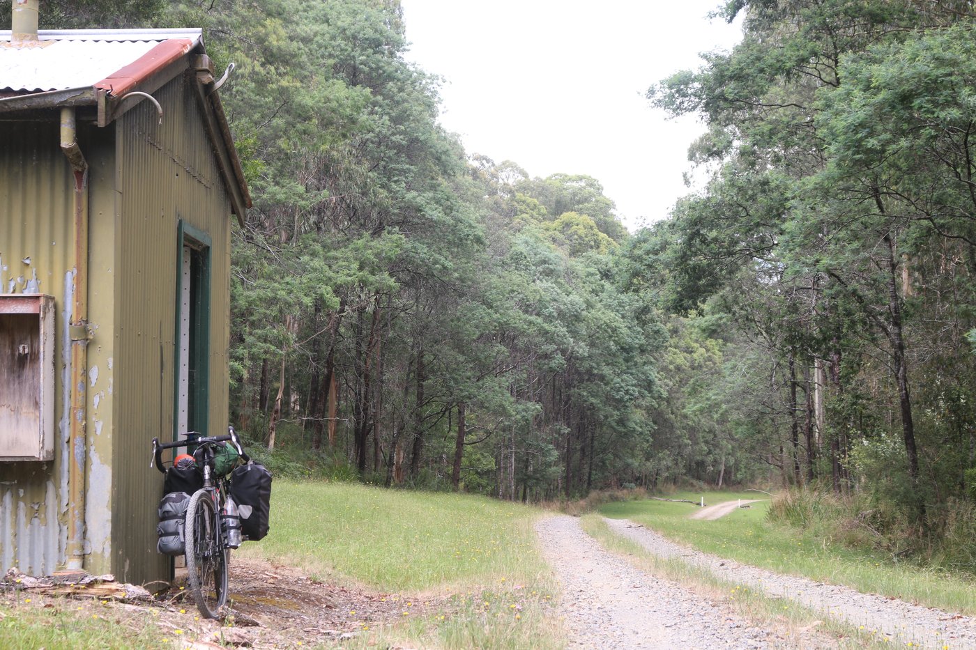 My bike leant against an abandoned shack beside a gravel track