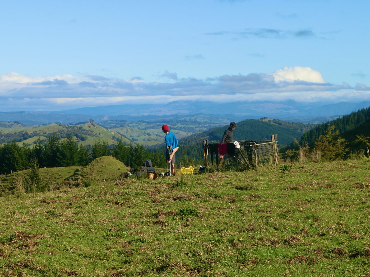 Mitch and Paul stretch and lay out their wet clothes after exiting the forest onto a hilltop.