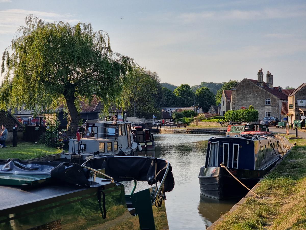 Several narrowboats moored along a populated stretch of the canal