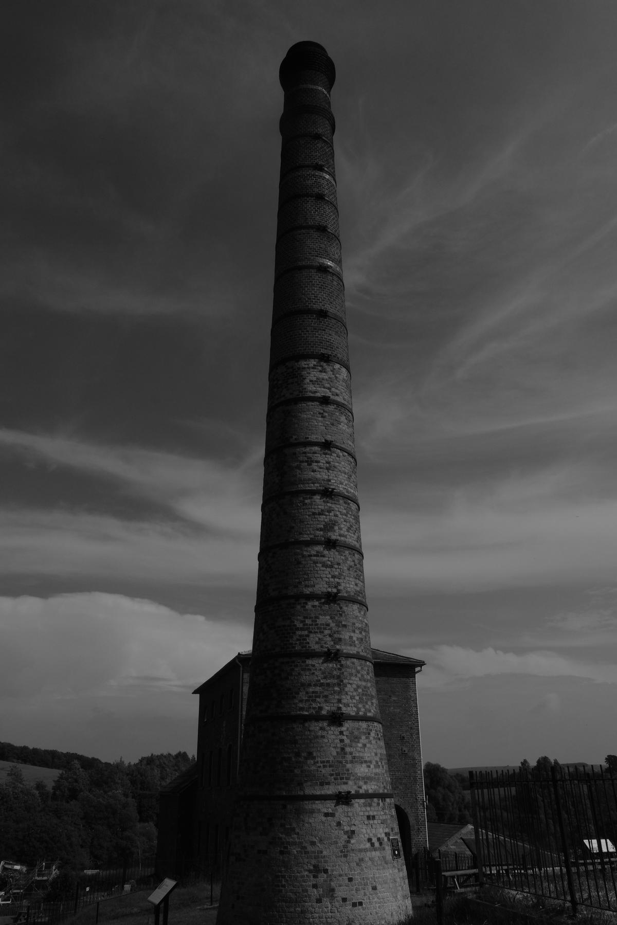 A smoke stack stands abandoned in the middle of the country side