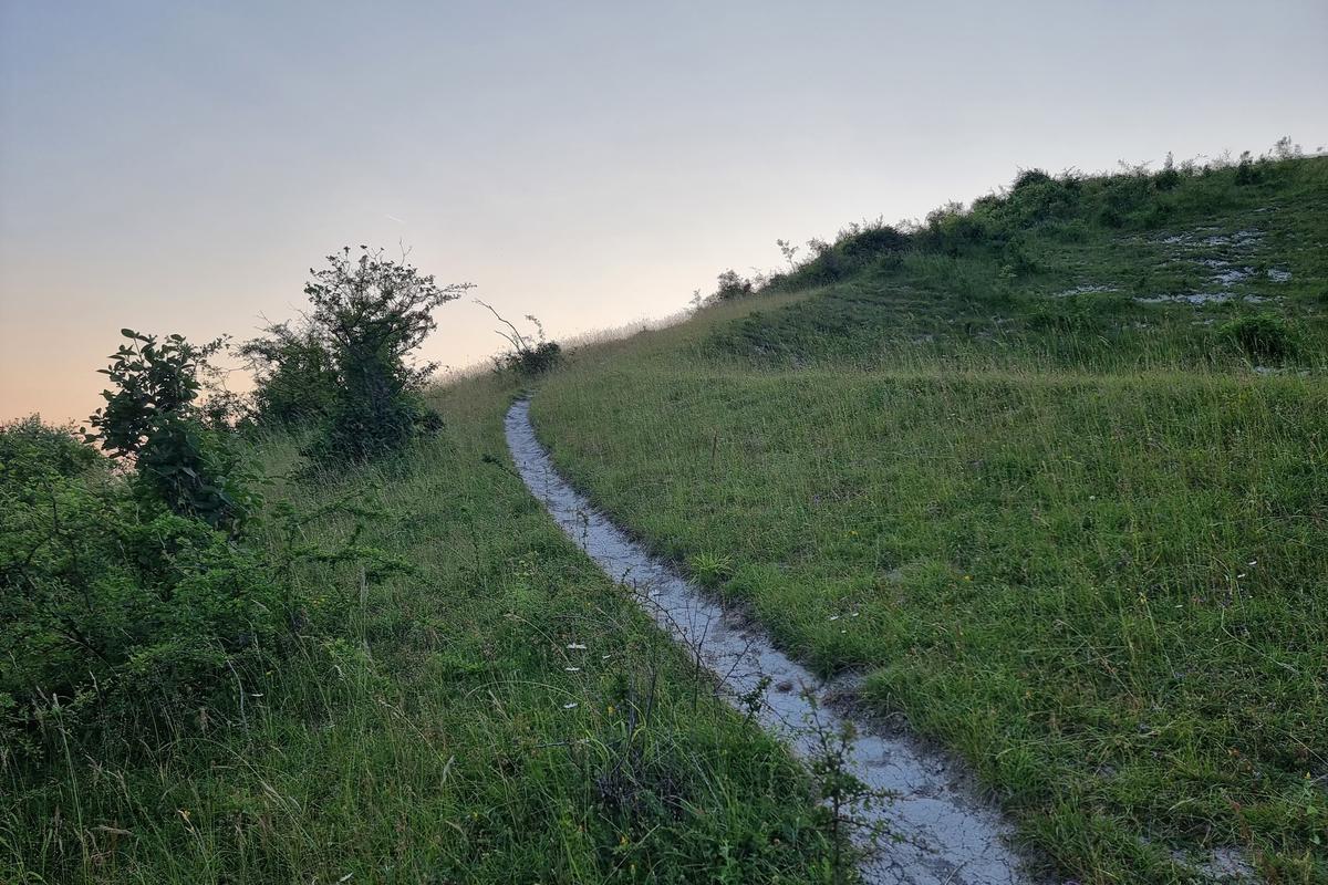 A chalky white path curves around a hill