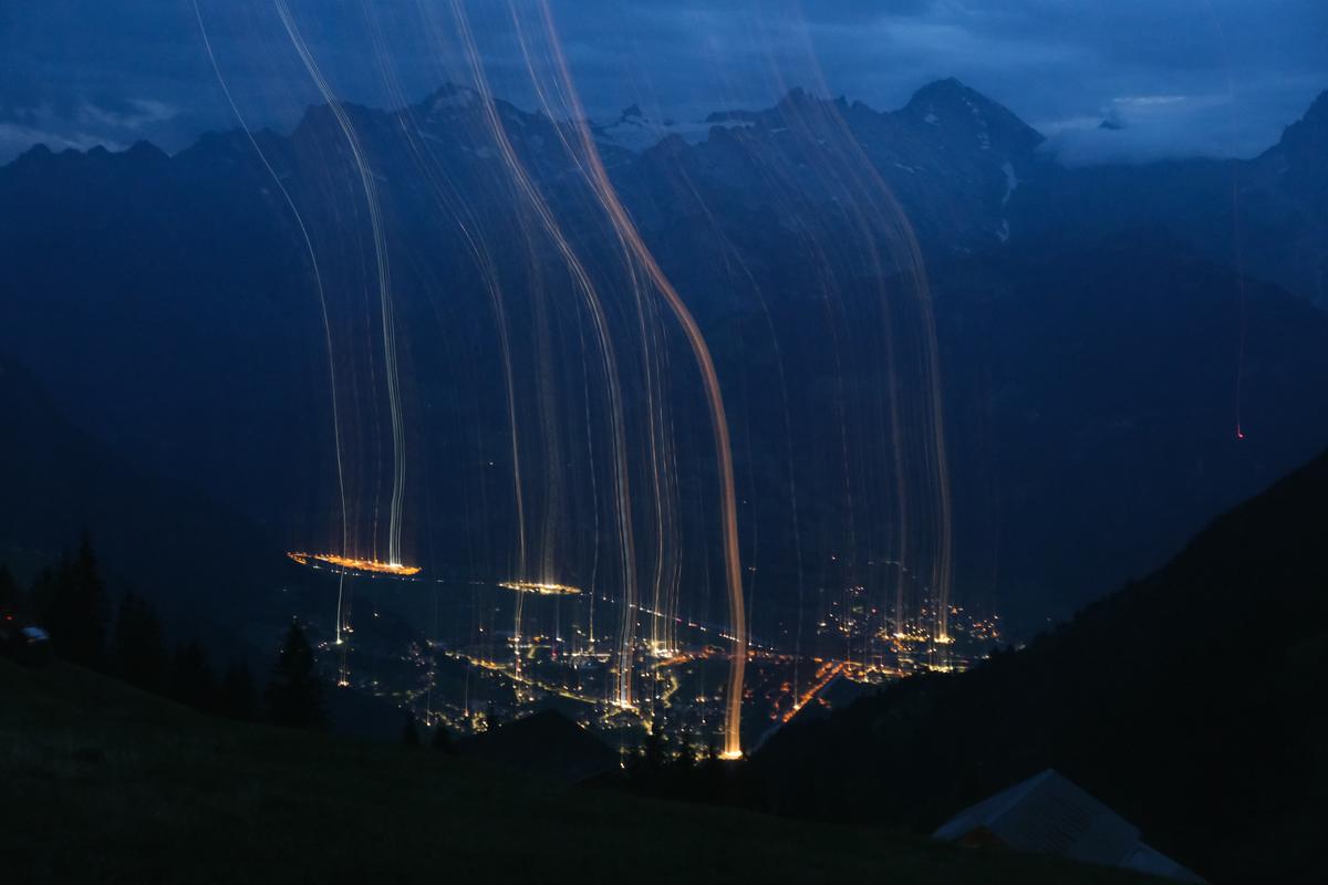 Creating wisps of light above a city viewed from the mountains using motion and a long exposure, Switzerland