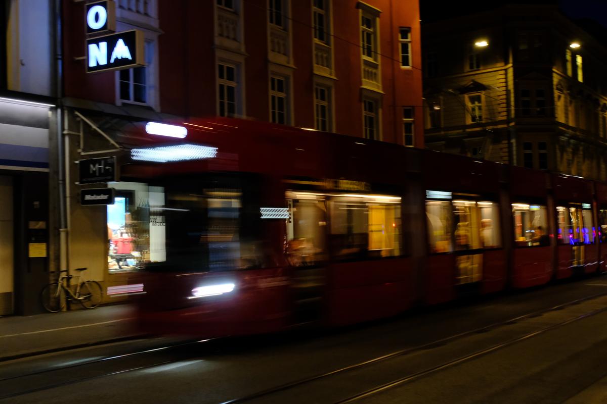 A tram speeds along a dark street in Innsbruck, Austria