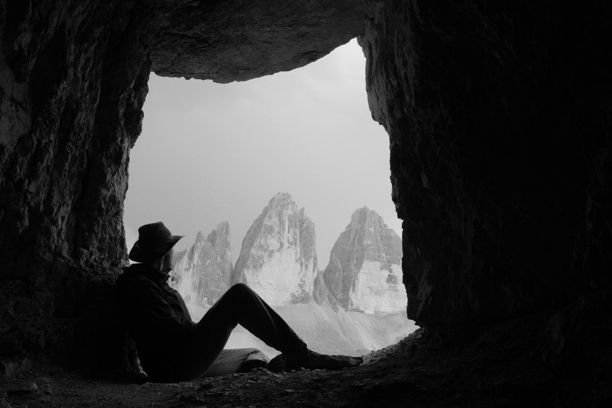 Sat in the entrance of a cave, my home for the night, on the side of Toblinger Knoten, Italy, looking across at Tre Cime do Lavaredo as a lightning storm rolls overhead