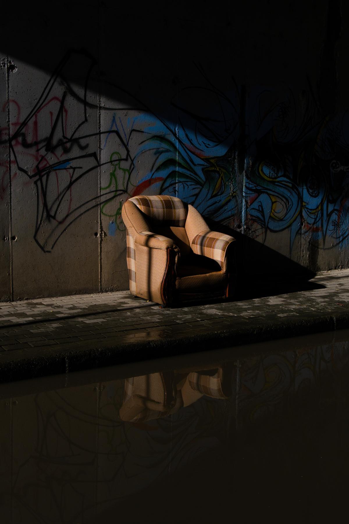 A discarded armchair sits just above the waterline of a flooded underpass. Tirana, Albania