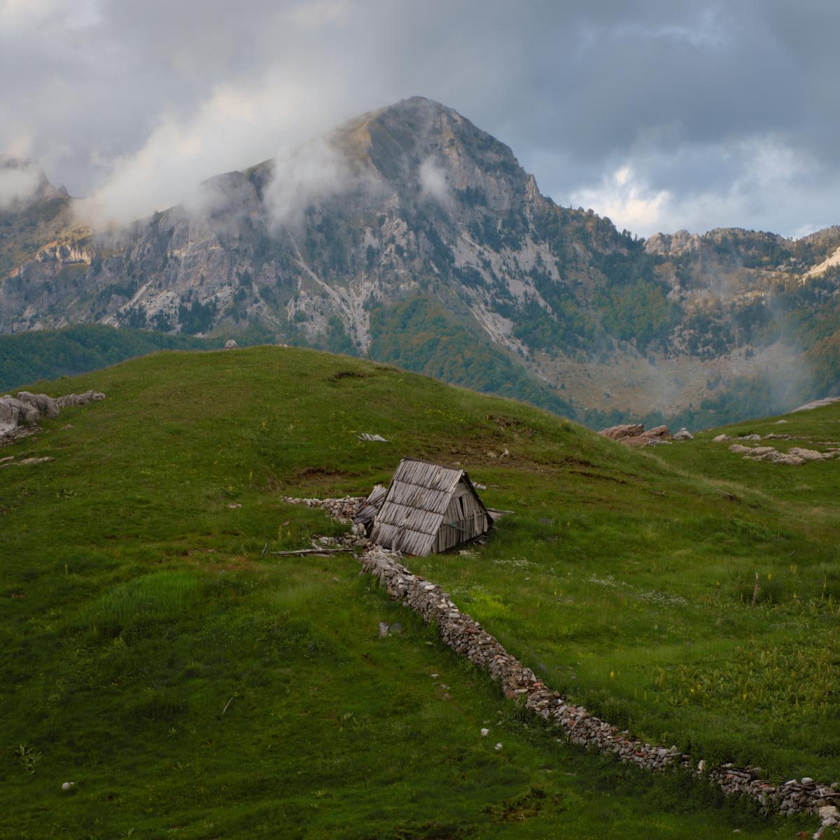 A dry stone wall leads to a disused shepherds hut in the mountains between Lepushe and Theth, Albania