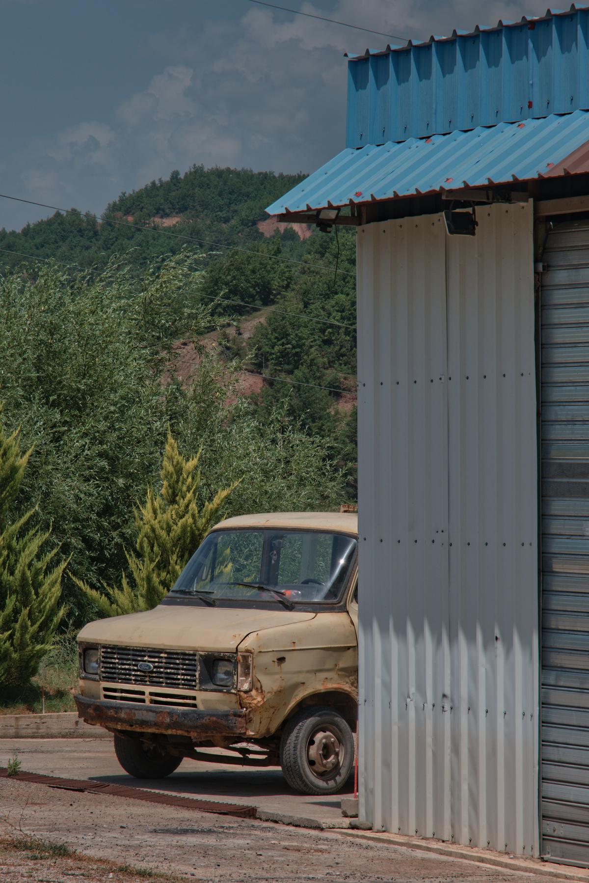 An old Ford farm truck pokes out from behind a corrugated shed near Labrazhd, Albania