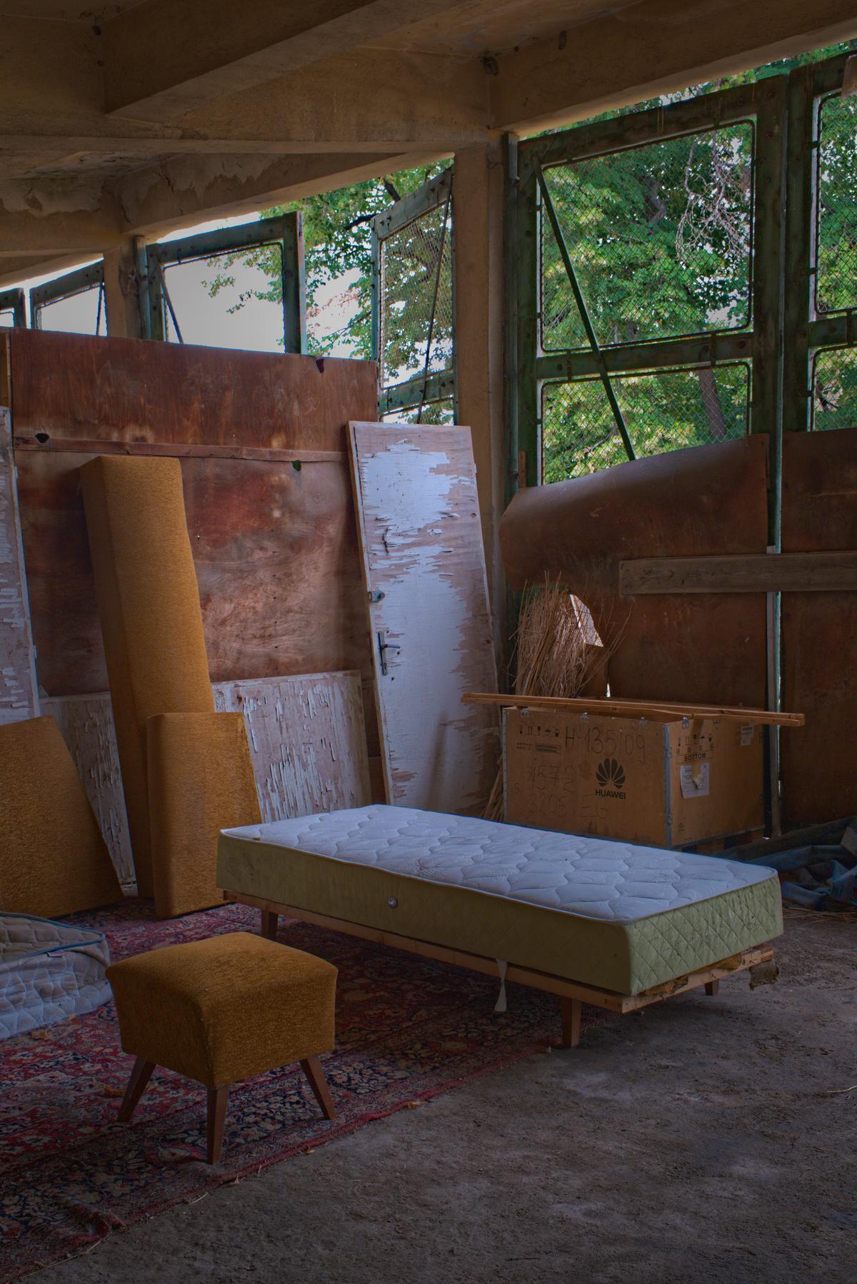 Hidden behind a mountain of trash and a wall of furniture in an abandoned shed lies a scene of serene (if spartan) domesticity. Plovdiv, Bulgaria 