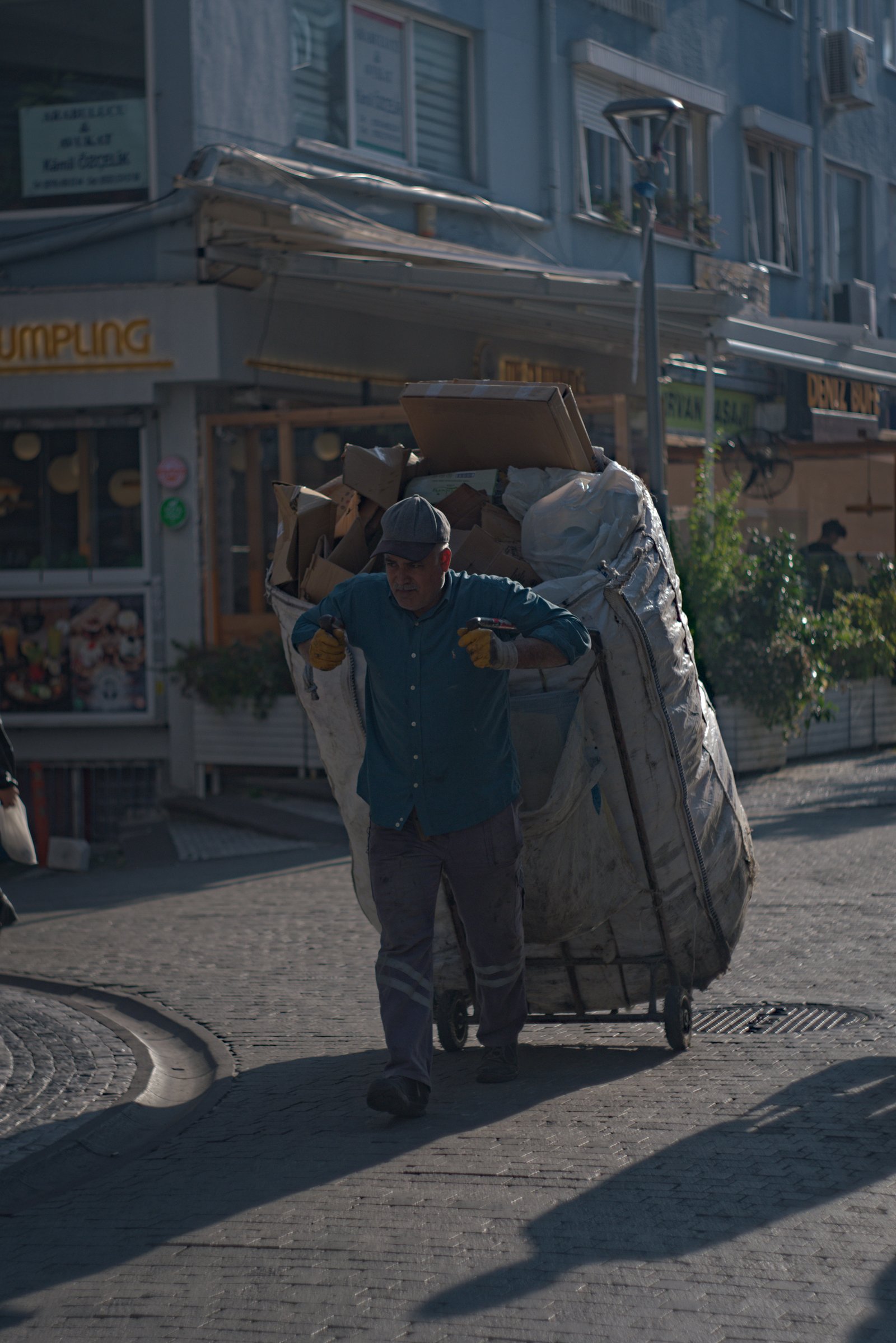 A man walks through the streets of Kadıköy pulling a bag of cardboard to be recycled. Istanbul, Turkey