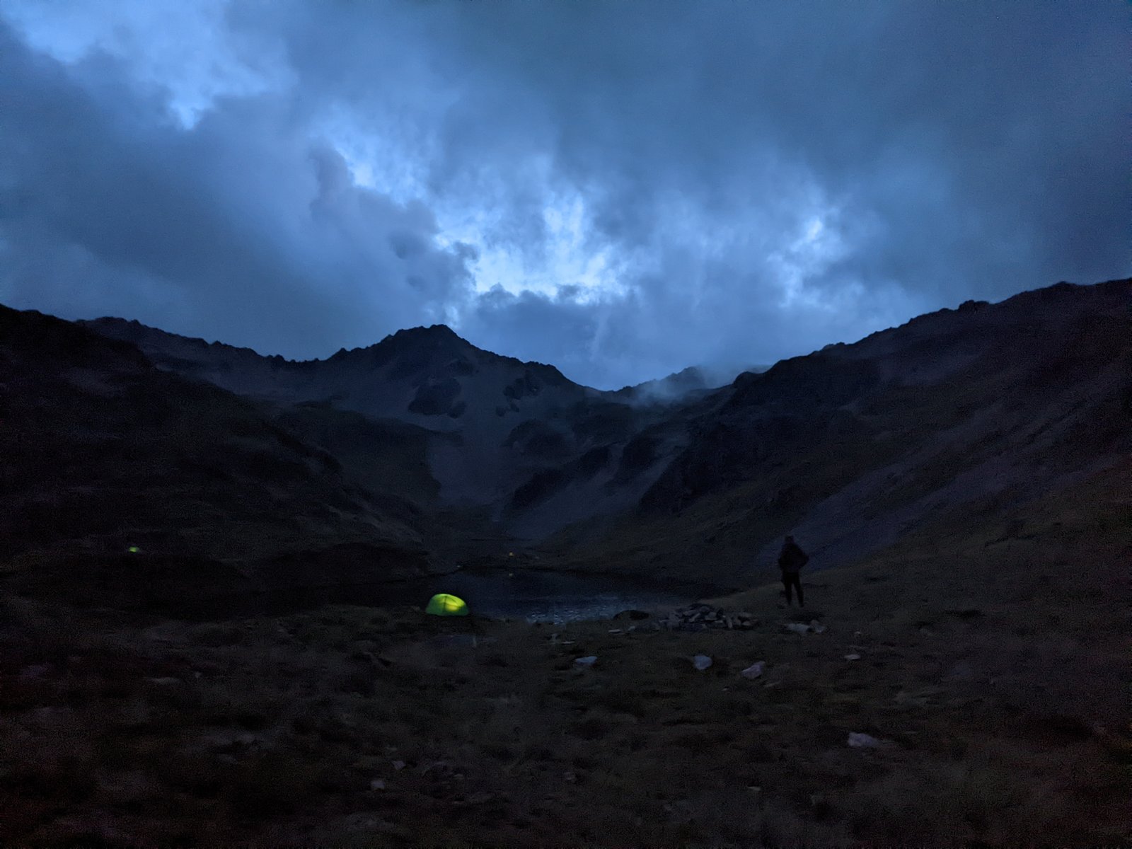 Lit from within, the tent glows at the edge of the tarn.