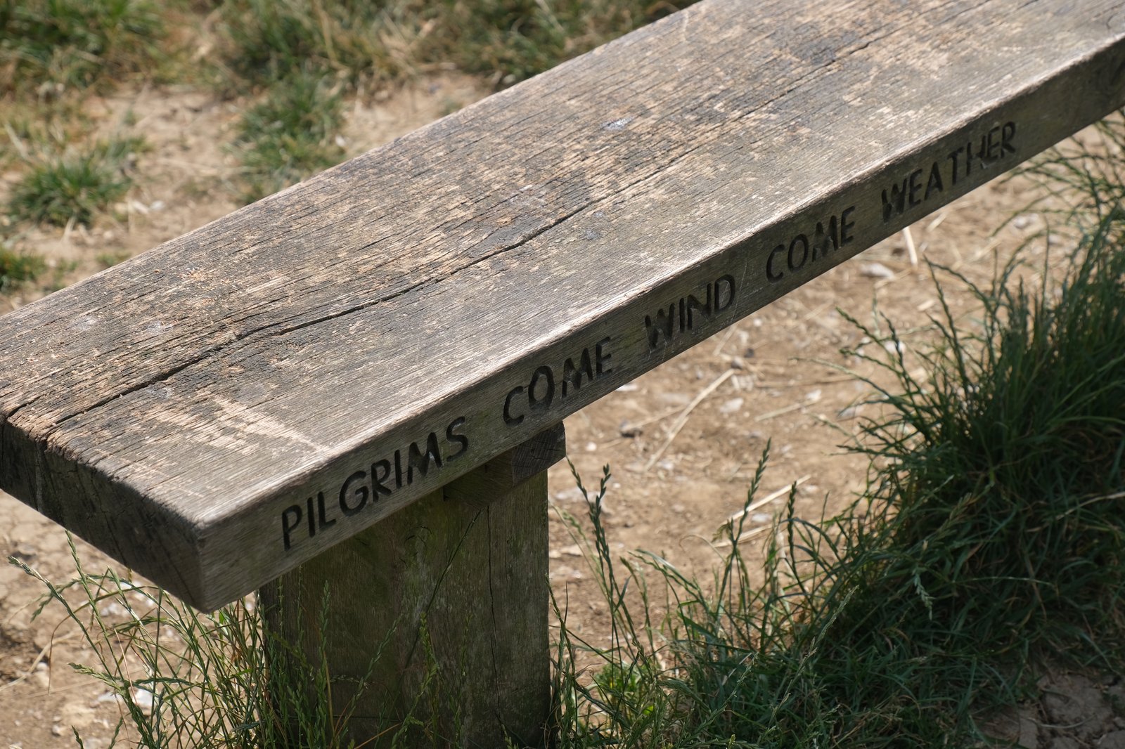 A bench reads 'Pilgrims come wind come weather'