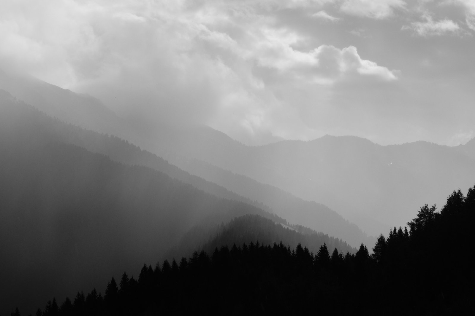 Stacked hills stretch into the distance. To the right the sky is clearing but to the left the rain still falls. Italy 