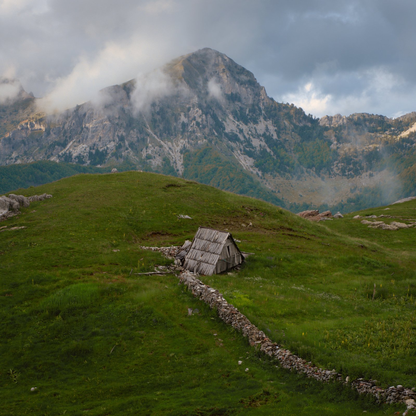 A dry stone wall leads to a disused shepherds hut in the mountains between Lëpushë and Theth, Albania