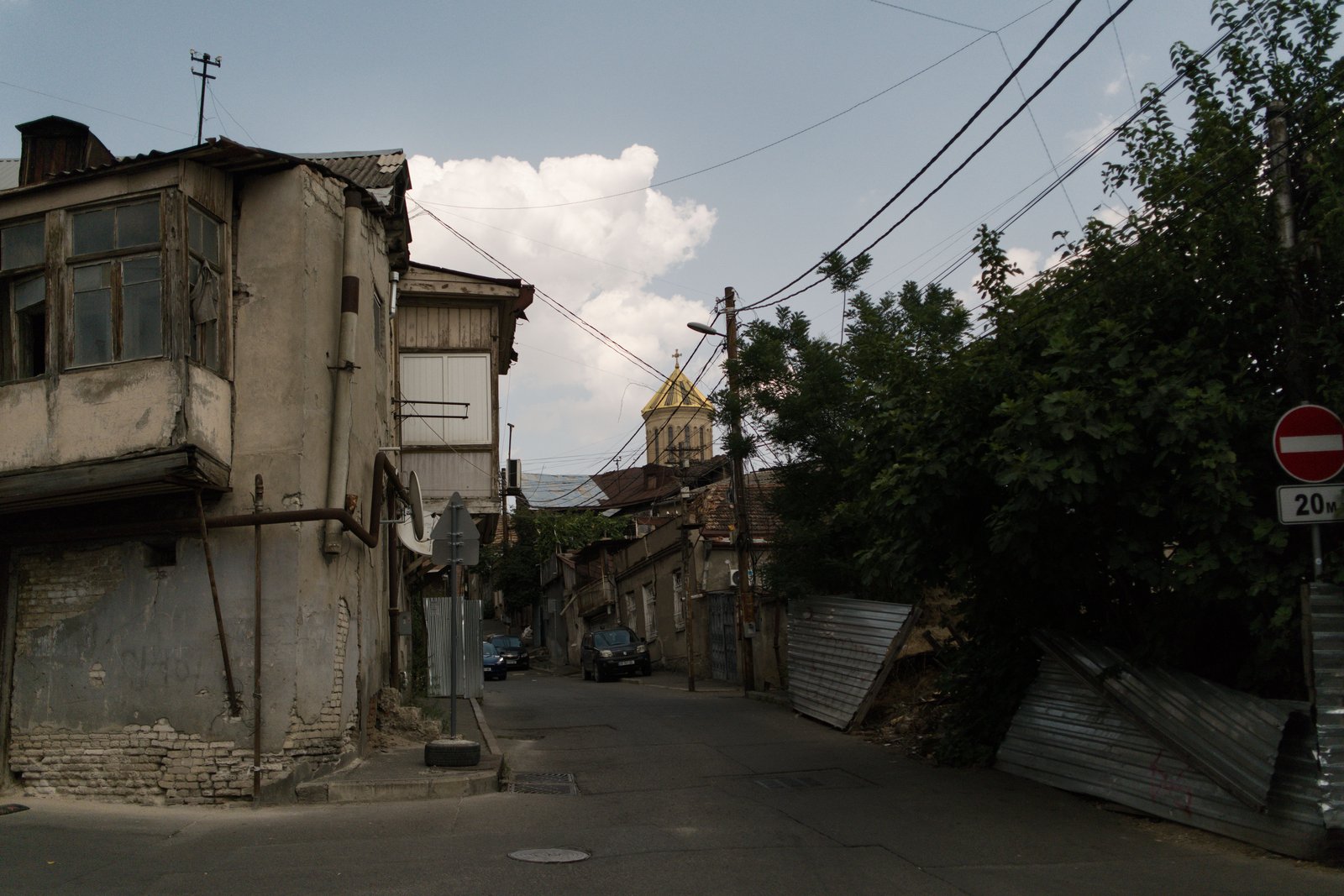 The spire of Holy Trinity Cathedral visible beyond a dilapidated street. Tbilisi, Georgia