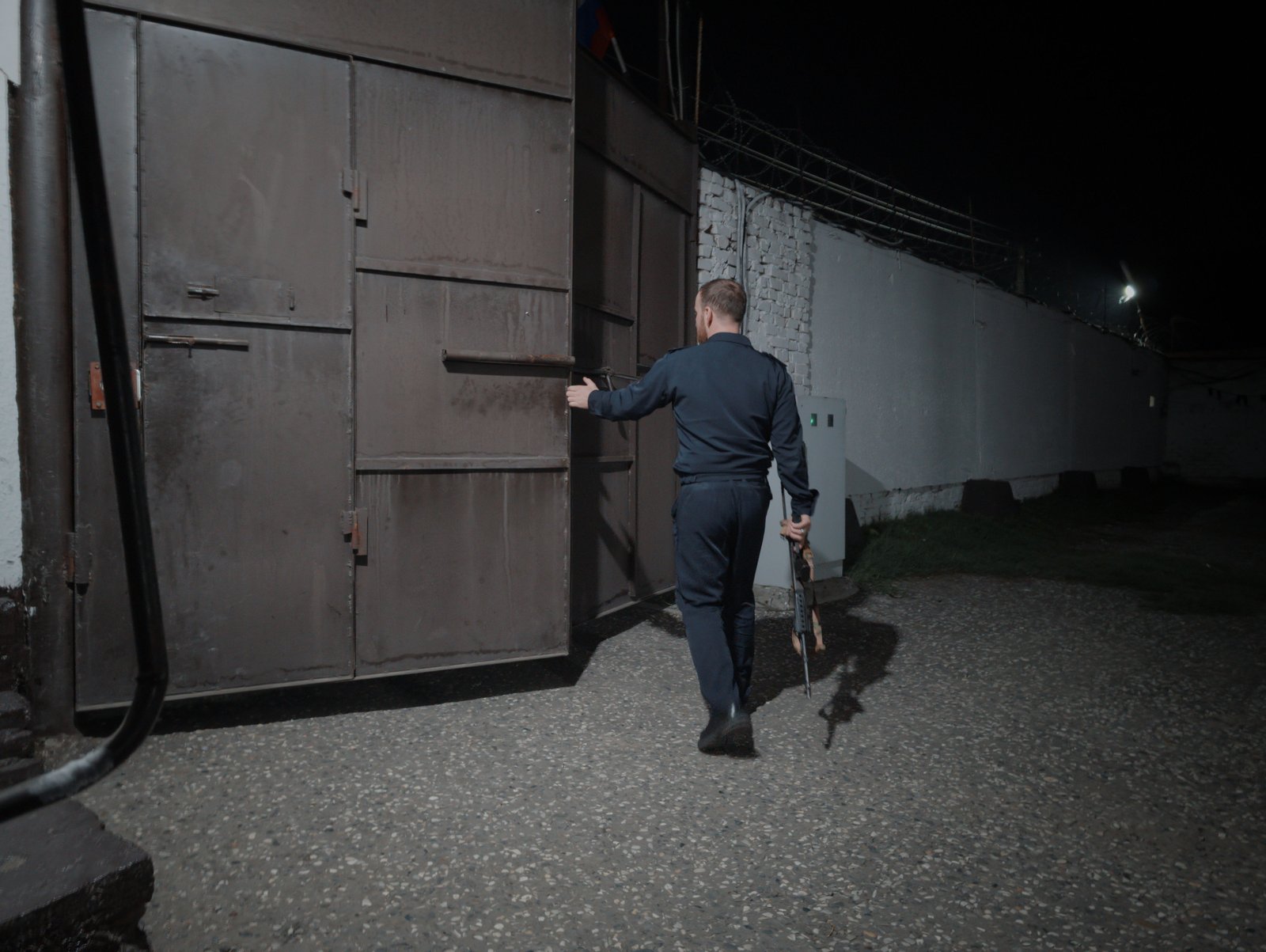A guard opens the gate to admit a returning patrol car at a police station in Chechnya while I wait to be released after what ends up being almost nine hours in custody.