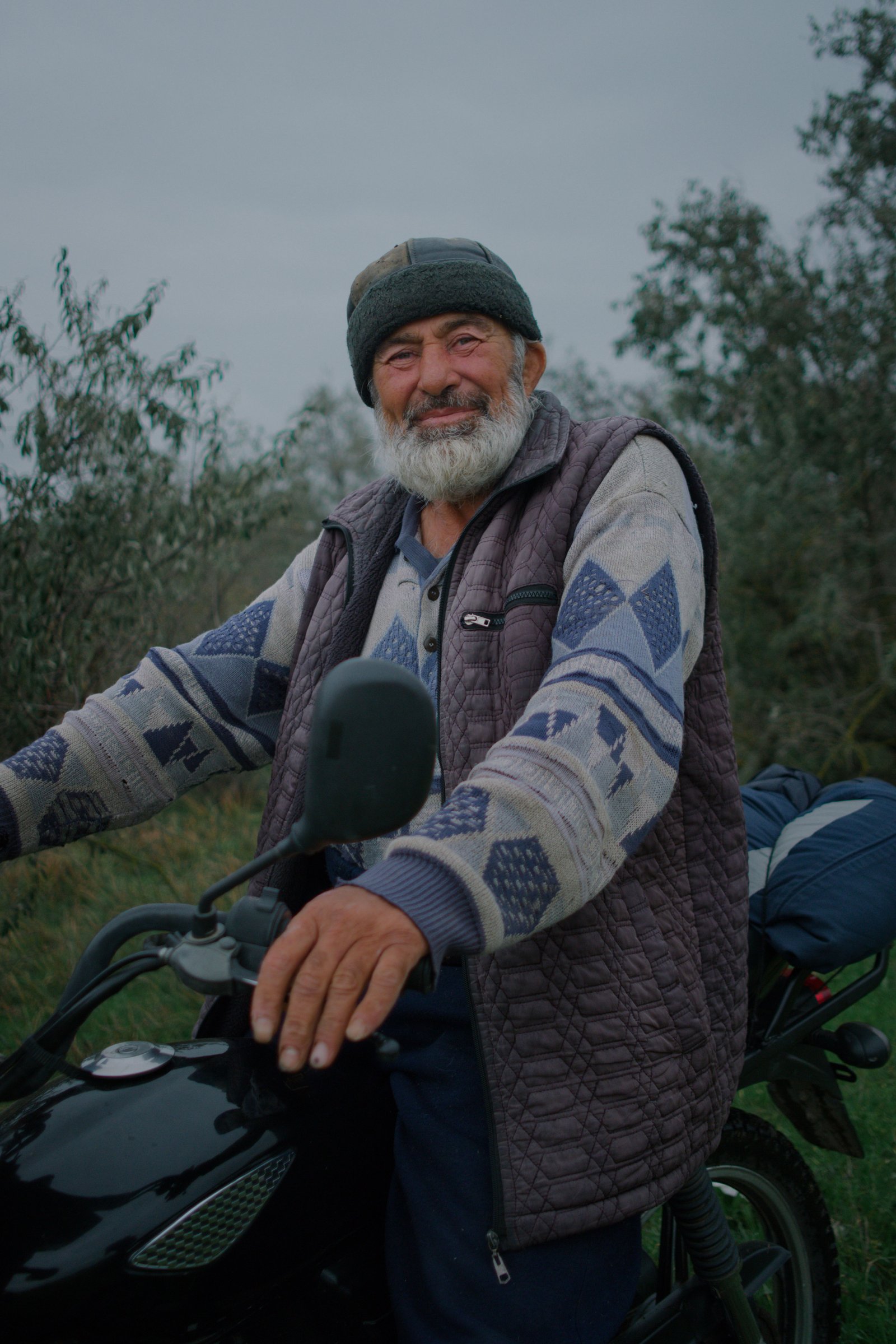 Muktar atop his motorcycle, rounding up his free-grazing cows for milking on a cool morning in Chechnya, Russia.