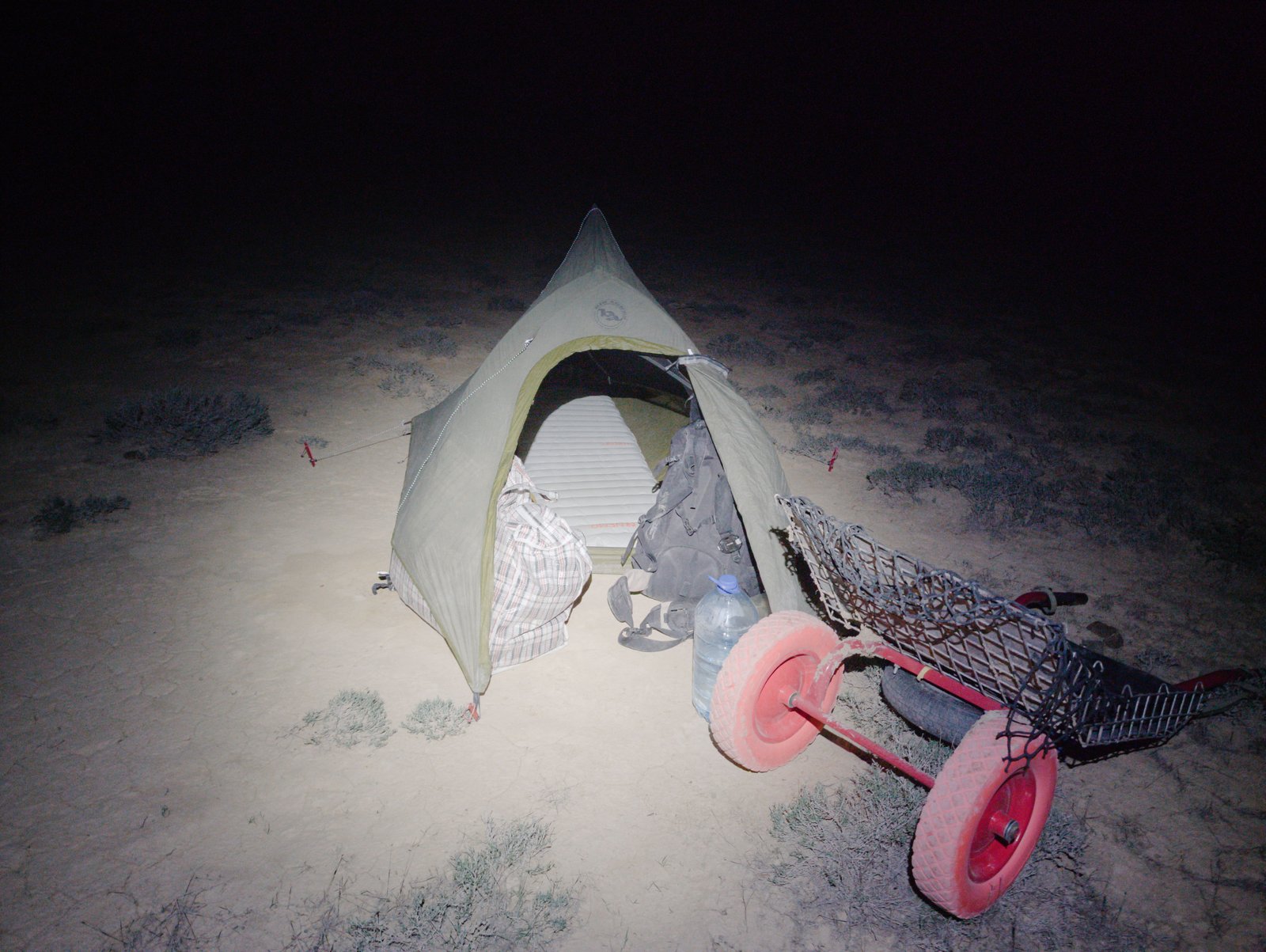 My tent pitched on the cracked surface of the desert. Mushke, my cart, beside it. Western Kazakhstan.
