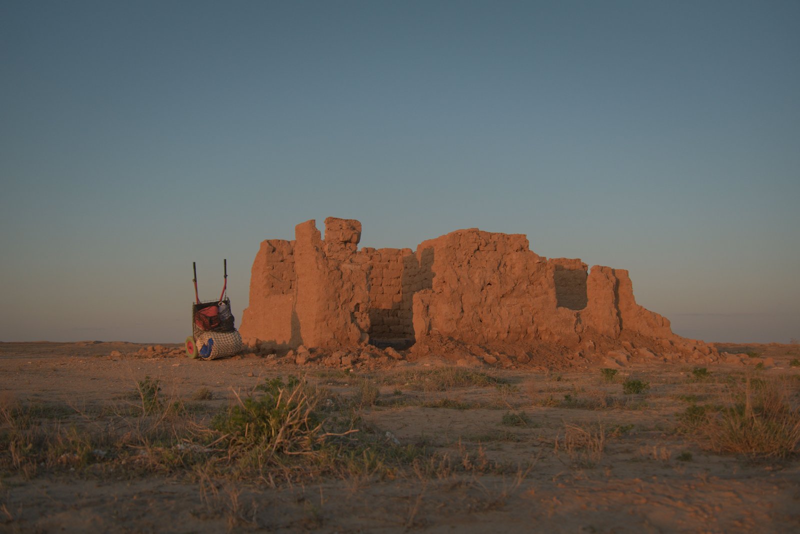 Mushke (my hand cart) rests beside a crumbling dwelling in the desert of the Ustyurt Plateau, Qaraqalpaqstan, Uzbekistan